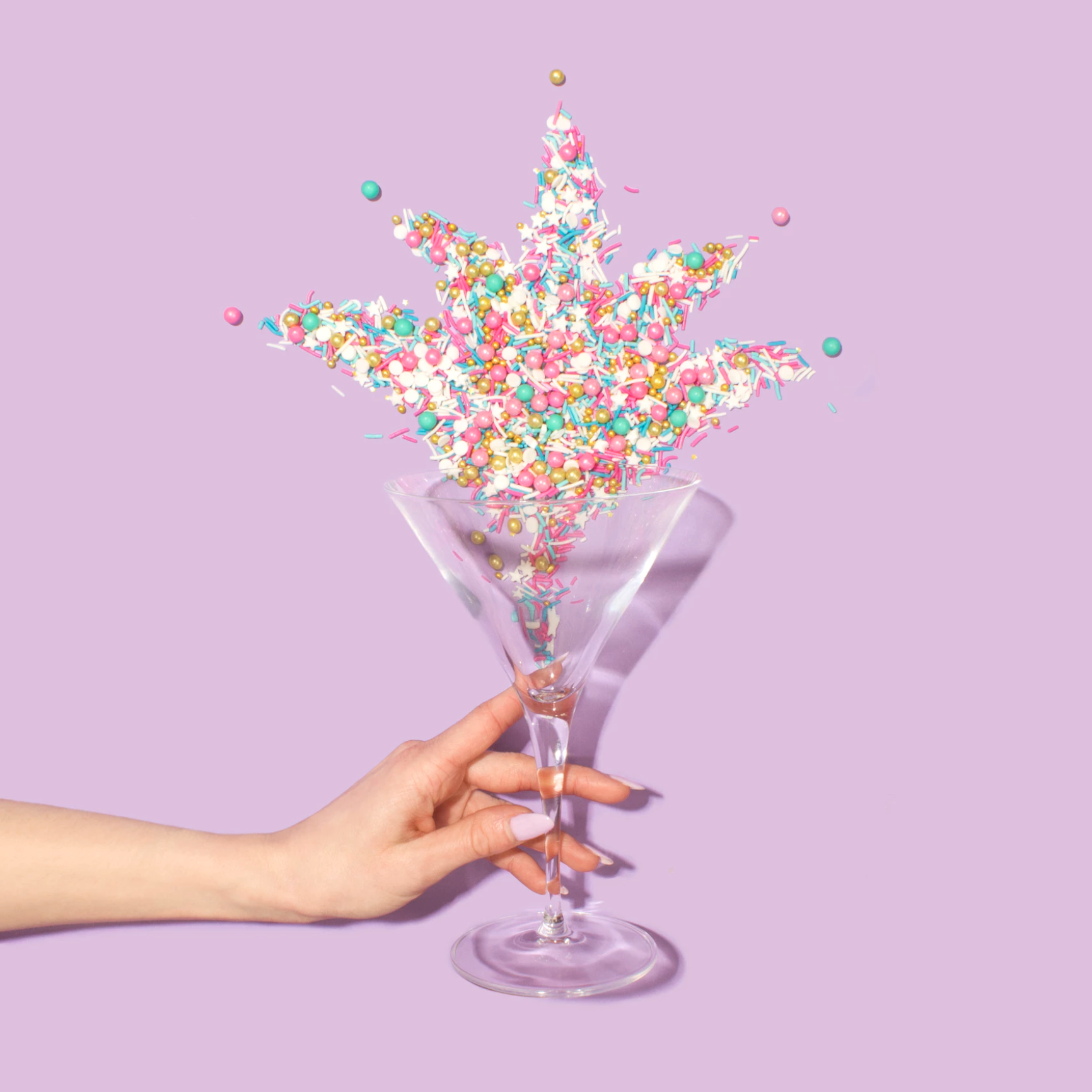 Sprinkles shooting up from a glass held by a hand.